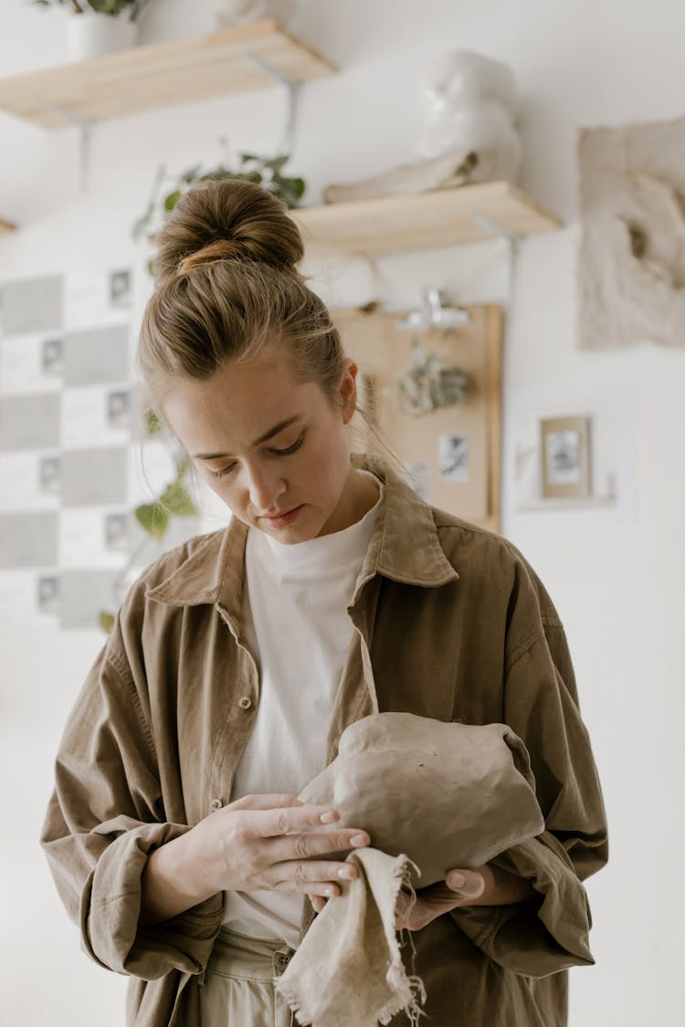 A Woman In Brown Long Sleeves Sculpting A Clay Pot