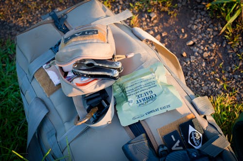 Free Khaki Backpack with Survival Kit on the Ground Stock Photo