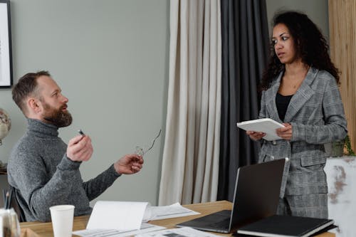 Free A Man and a Woman Discussing in an Office Stock Photo