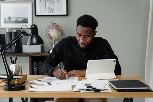 Free Businessman in a modern office working on documents using a digital tablet. Stock Photo