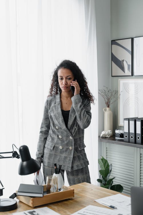 A Woman in Gray Blazer Using a Smartphone in an Office