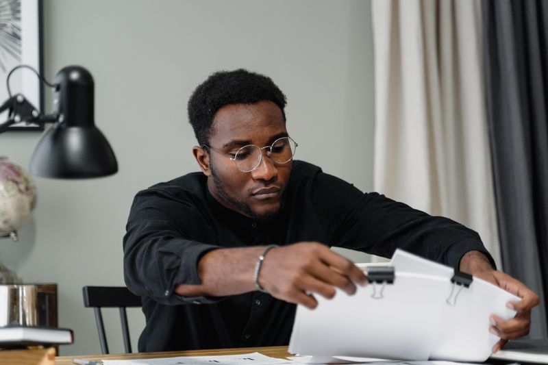 Professional man with glasses reviews documents at a desk in an office setting
