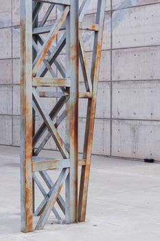 Close-up of a rusty metal structure against a concrete wall in an industrial setting.