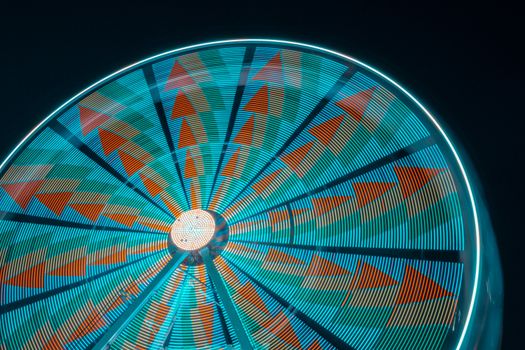 A captivating long exposure shot of an illuminated Ferris wheel at night, showcasing vibrant colors and motion.