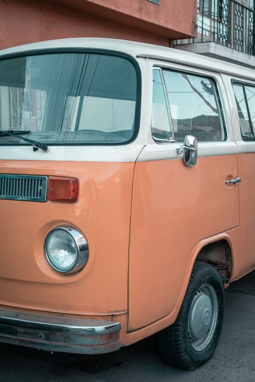 Free A classic orange Volkswagen camper van parked in a city street, perfect for retro and transportation themes. Stock Photo
