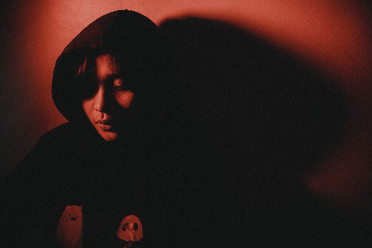 artistic portrait of a person in a hood illuminated by red light creat