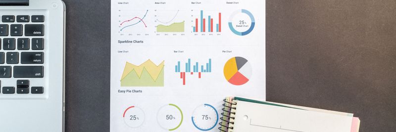 Top-down view of a desk with charts, a laptop, and notebooks, ideal for data analysis themes.