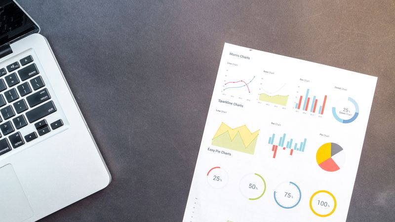 Modern desk setup with a laptop and analytical charts showcasing data interpretation and business analysis.