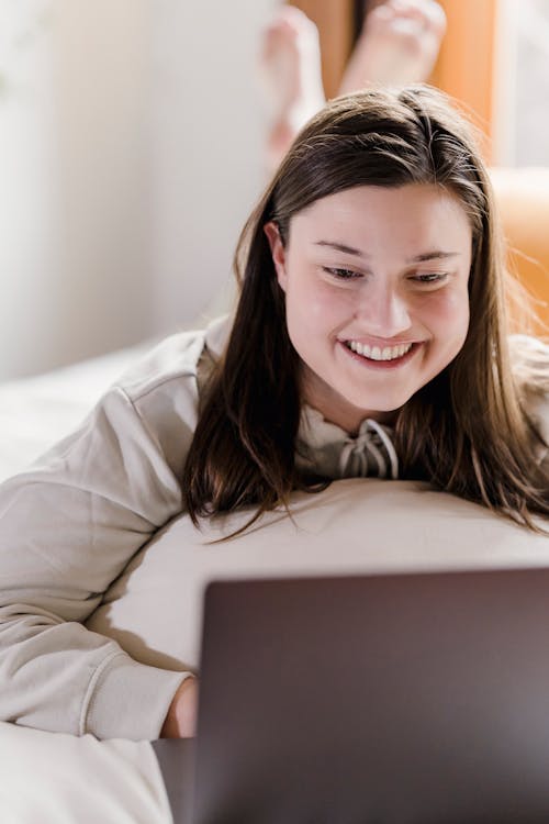 Free Smiling woman browsing laptop in bedroom Stock Photo