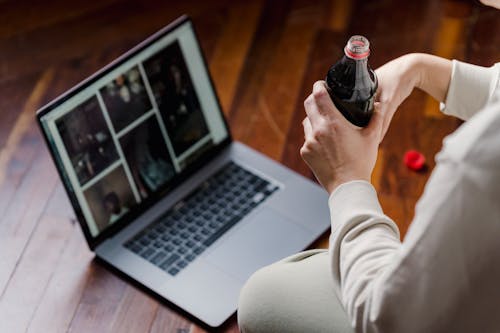 Crop person with soda sitting on floor with laptop