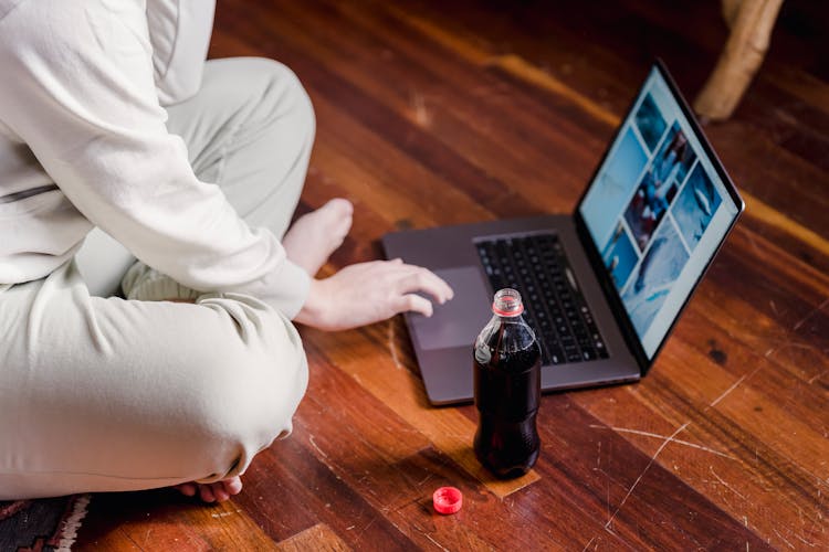 Crop Person Using Laptop On Floor