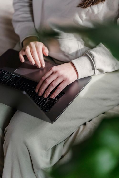 Free From above of unrecognizable female freelancer typing on keyboard of netbook while sitting in light room with green plants at home Stock Photo
