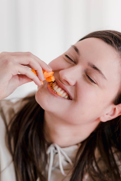 Smiling woman eating tasty stick corn chips
