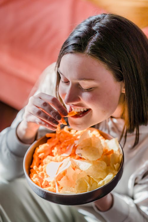 Free Hungry happy woman eating chips in bowl Stock Photo