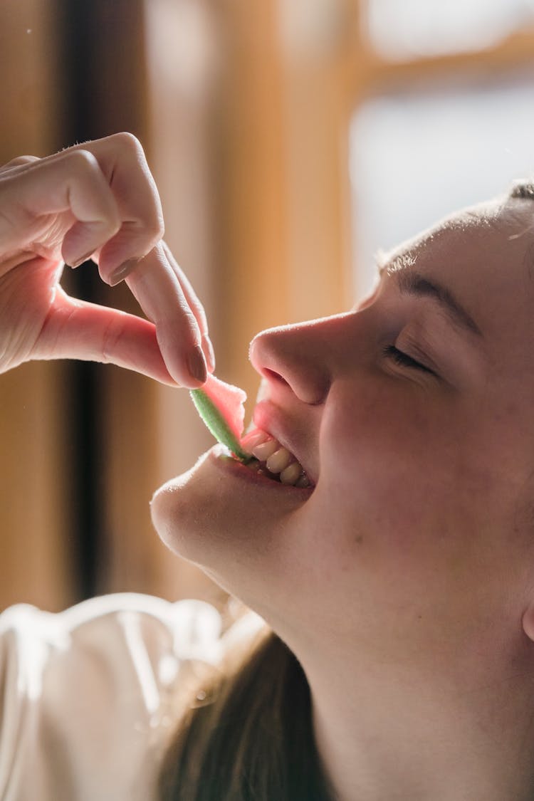 Glad Young Woman Biting Sweet Marmalade