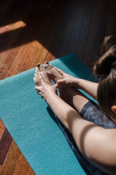 A woman performs a yoga stretch on a blue mat indoors, emphasizing flexibility and wellness.