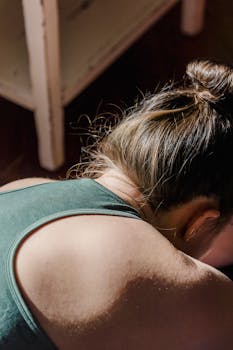 A woman performing a yoga pose indoors in natural morning light, creating a calm and focused atmosphere.
