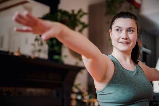 A young woman performing a yoga pose indoors, focusing on exercise and wellness.