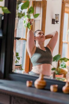 Woman doing yoga in a bright room with plants, promoting relaxation and wellness.