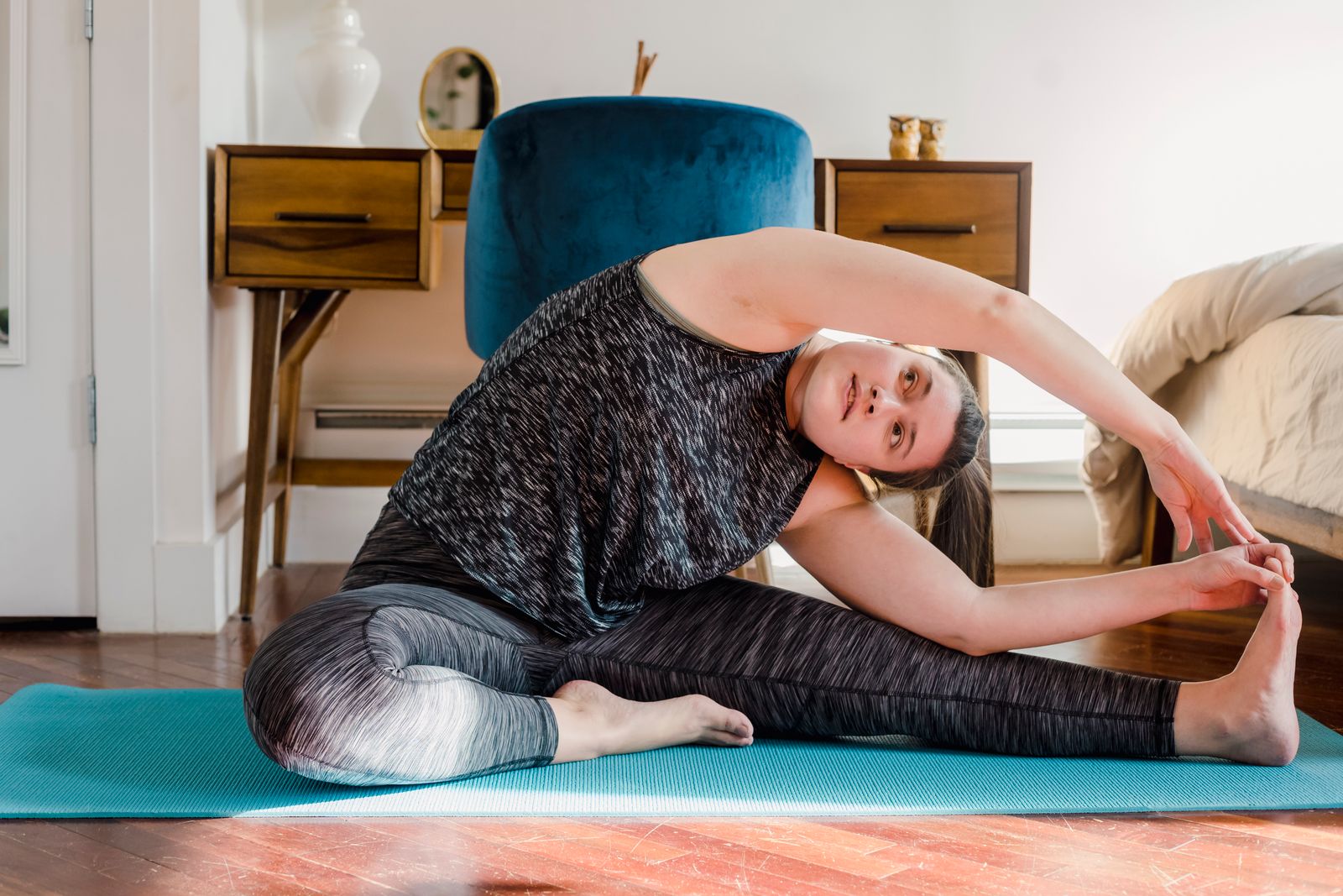 Woman practicing a gentle seated yoga stretch on a mat at home during her period