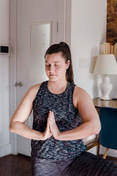 A woman practicing yoga indoors, focusing on relaxation and mindfulness in a home setting.