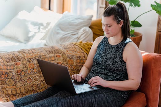 Woman lounging on a couch with a laptop, enjoying a relaxed moment in a cozy indoor setting.