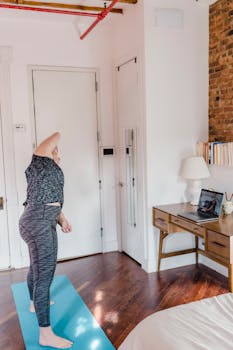 A woman doing yoga on a mat in a well-lit bedroom, enhancing indoor exercise routines.