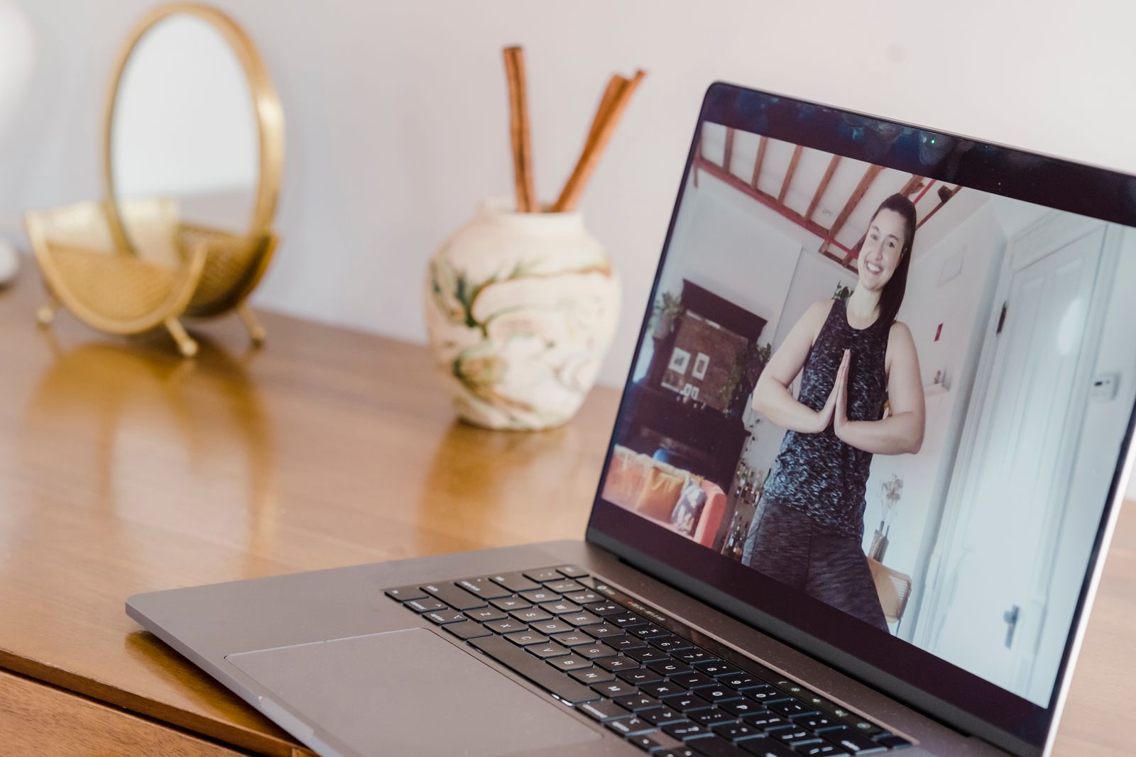 Woman following an online yoga class on a laptop screen from her living room