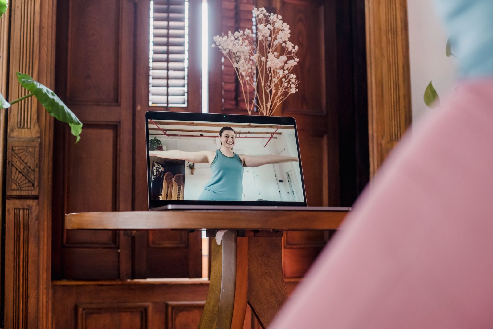 Woman following a live yoga class online on a laptop in her living room