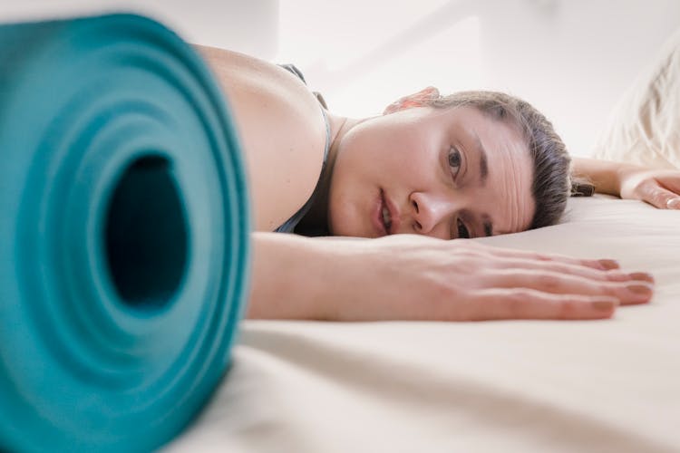 Tired Woman Lying On Bed During Workout