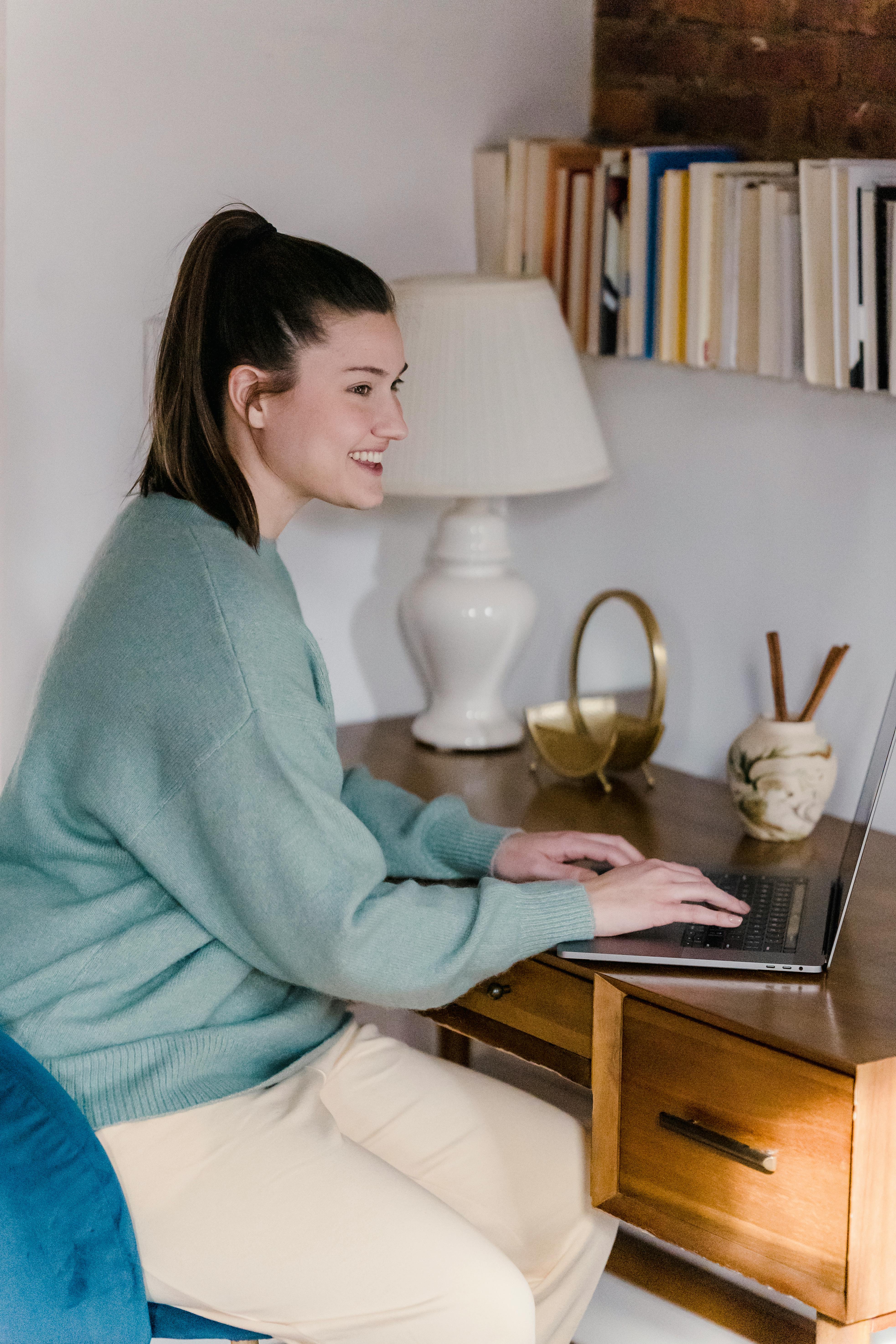 positive young woman browsing laptop in bedroom