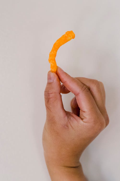 Free Bright orange crispy snack between fingers Stock Photo