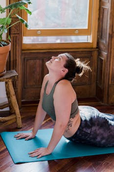 A woman performing a yoga pose on a mat indoors, bathed in morning sunlight.