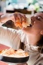 Young female eating pile of chips with closed eyes at home