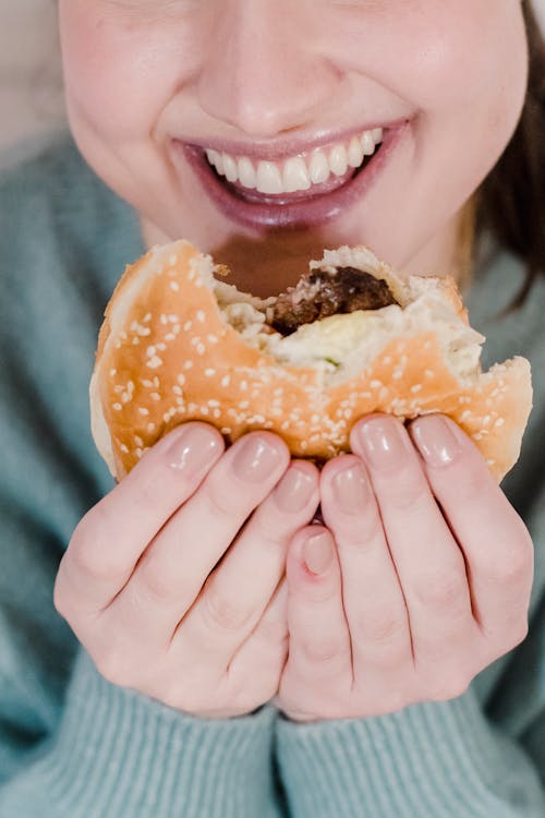 Woman smiling and eating hamburger with delicious cutlet