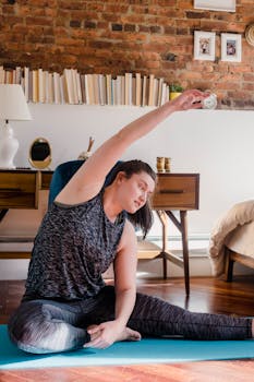 Adult woman in activewear stretching on a yoga mat indoors.