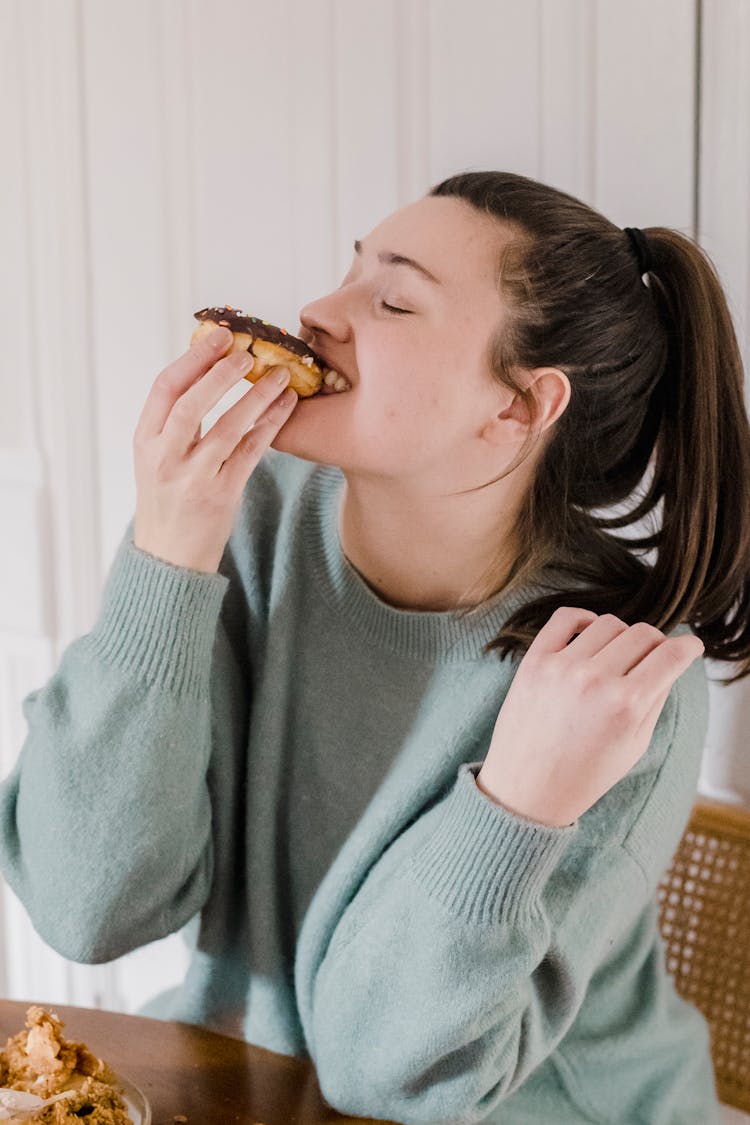 Woman Eating Sweet Chocolate Donut At Home