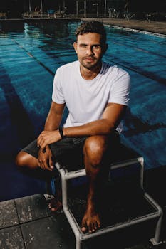 A young man sitting confidently at a poolside, embracing a calm and relaxed atmosphere.