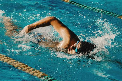 Free From above of anonymous male in goggles swimming in azure clean water of swimming pool Stock Photo
