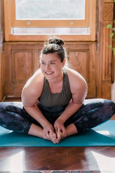 A happy woman enjoying a yoga session indoors with natural light.