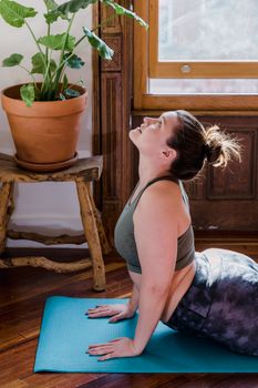 A woman performs yoga on a mat at home, embracing morning light and tranquility.