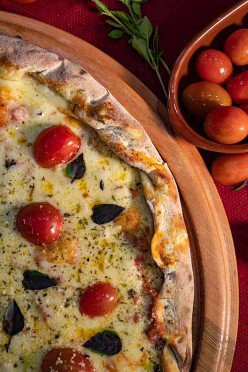 Free Close-up of a freshly baked Margherita pizza with cherry tomatoes and basil. Stock Photo