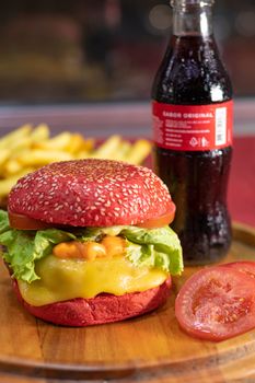 Vibrant red burger with cheese and lettuce, served with fries and soda.