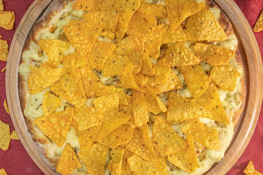 Close-up of a pizza topped with crunchy nacho cheese corn chips on dough.