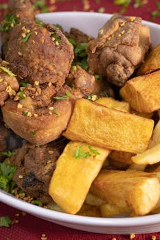 Crispy fried chicken served with golden potato fries, garnished with herbs for a mouth-watering meal.
