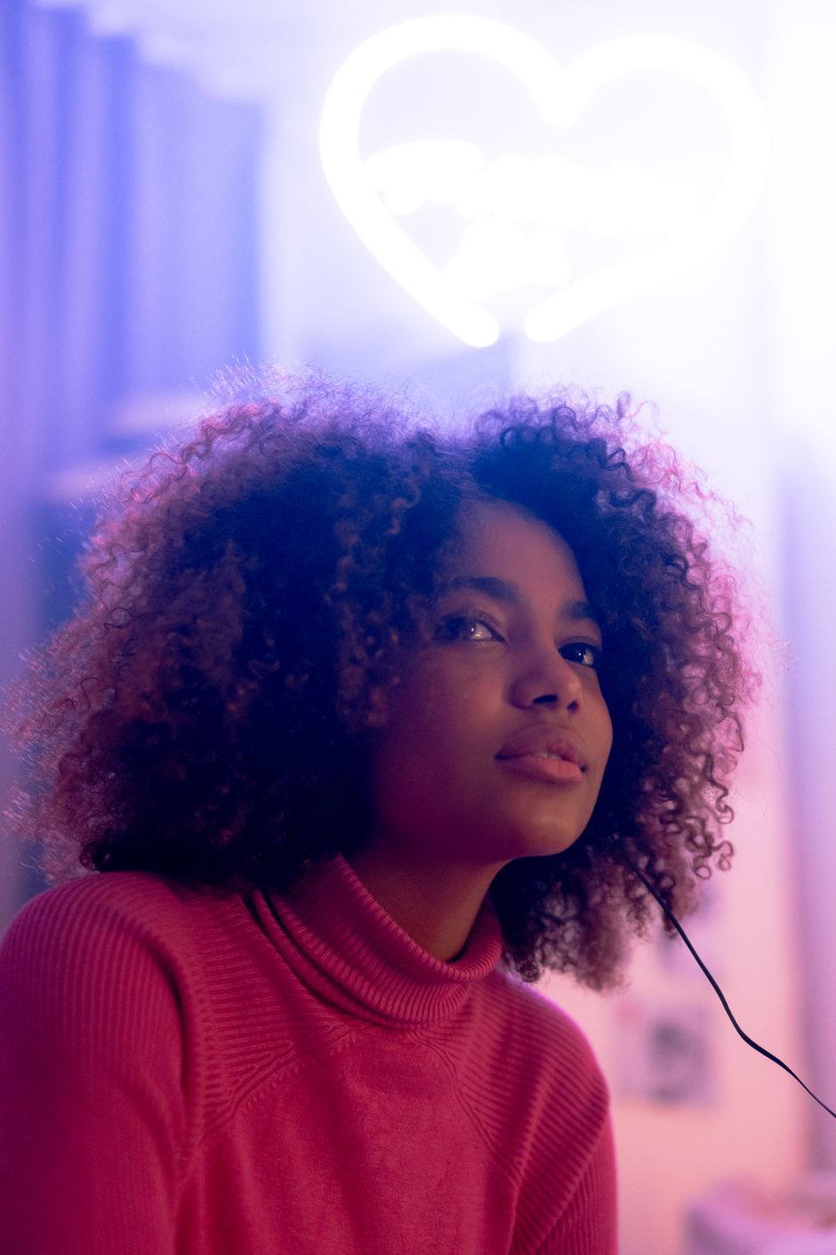 Young woman in a red turtleneck posing against a glowing backdrop