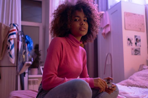 A Young Woman in a Red Turtleneck Sweater Sitting on a Bed