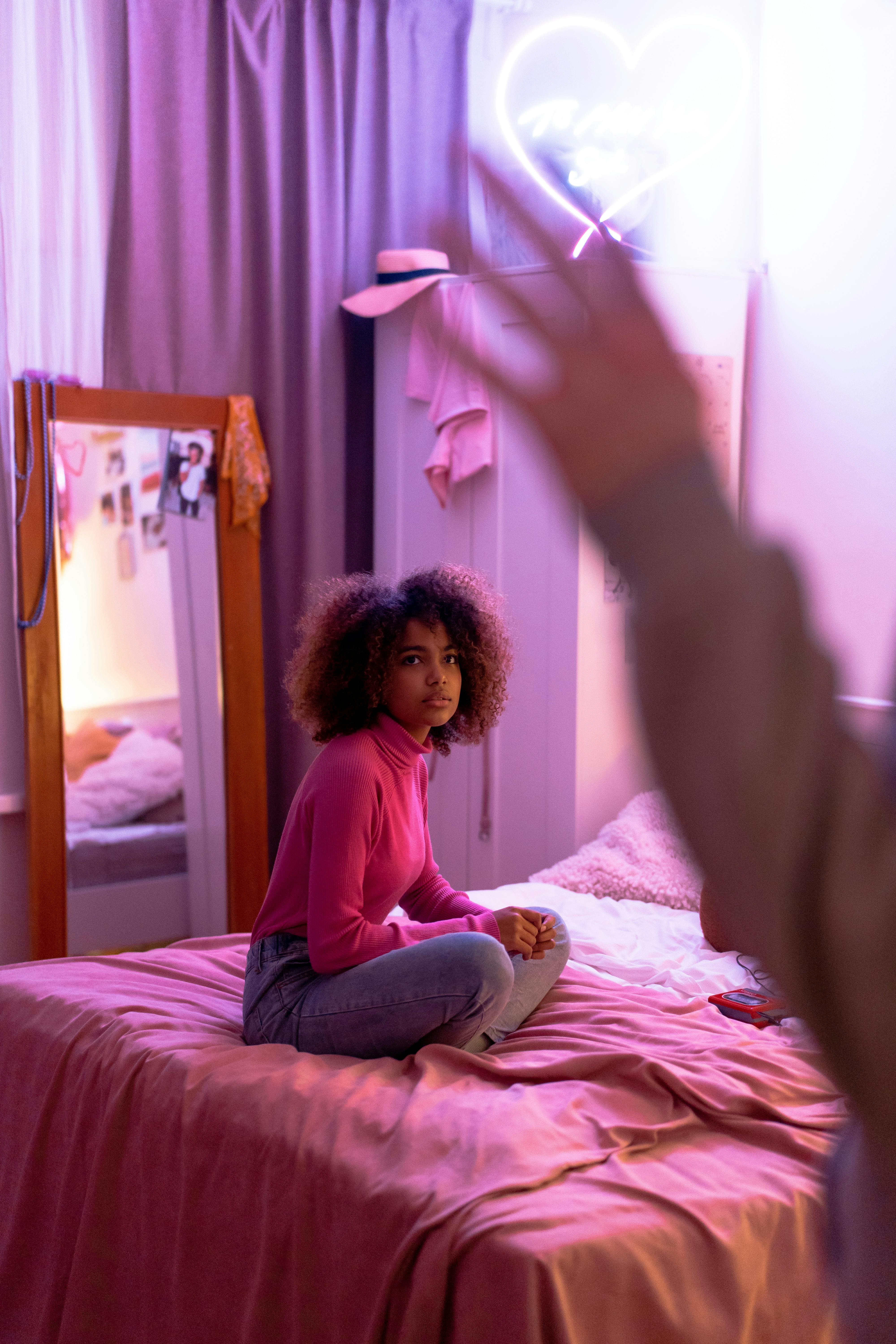 a young woman in a red turtleneck sweater sitting on a bed