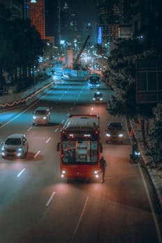 A vibrant night scene of traffic in Jakarta featuring buses and cars on a busy city road.