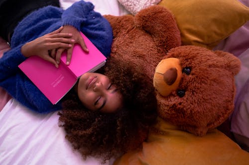 Woman Lying Down on Bed With Her Teddy Bear